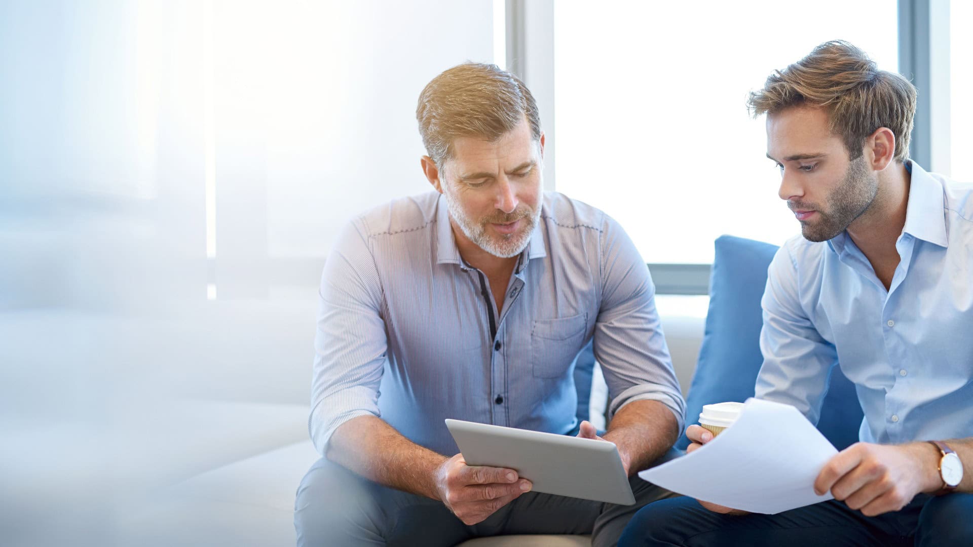 Mature businessman talking with younger colleague on couch jpg