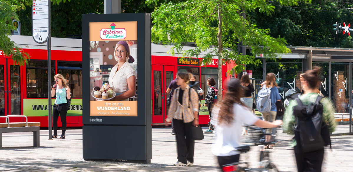 Eine blonde Frau mit freundlichem Lächeln hält Eisbecher auf farbigem Werbebild