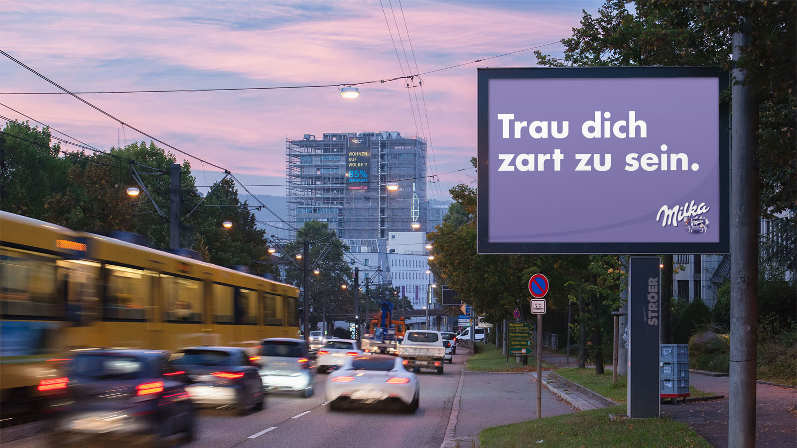 Eine belebte Straße bei Sonnenuntergang mit Milka Werbetafel und vorbeifahrenden Autos