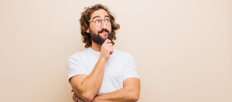 Mann mit nachdenklichem Blick in weissem Shirt und lockigen Haaren