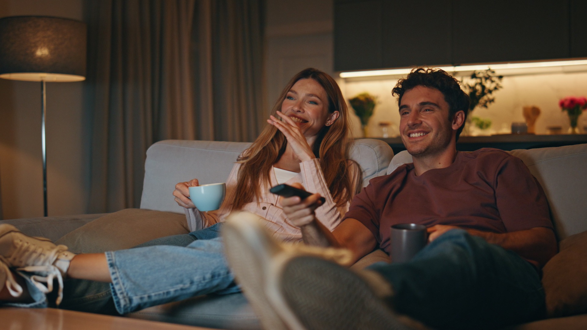 Married couple resting couch together. Smiling husband switching tv channels