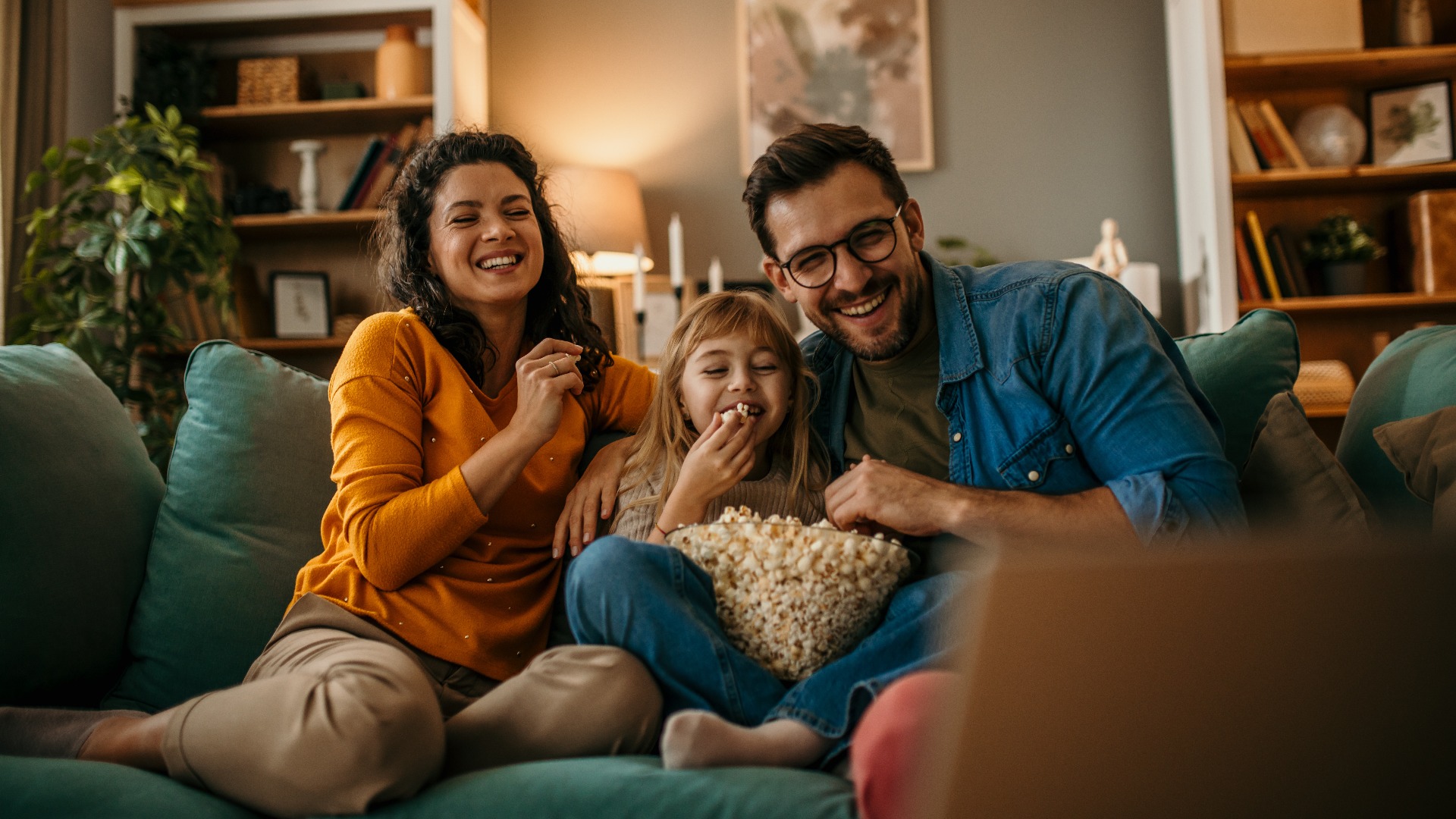The joy of togetherness as a mom, dad, and daughter share a movie and popcorn in their living room