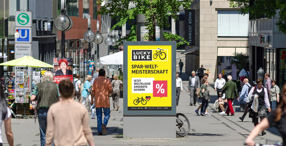 Belebte Einkaufsstrasse mit Passanten, neutral, gelbes Fahrradplakat, gruenes U Schild
