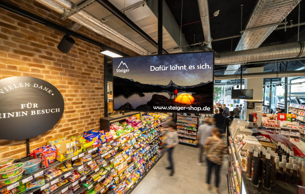Ein moderner Supermarkt mit grossem Werbebildschirm und bunten Suesswarenregalen