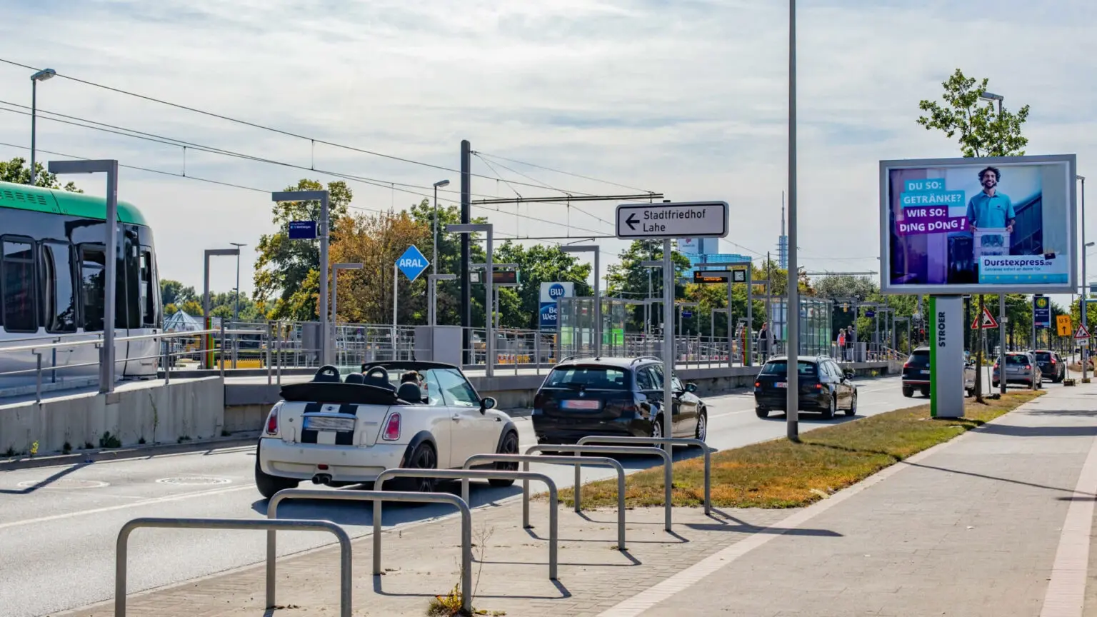 Strassenszene mit Werbetafel auf der ein laechelnder Mann Getraenke praesentiert